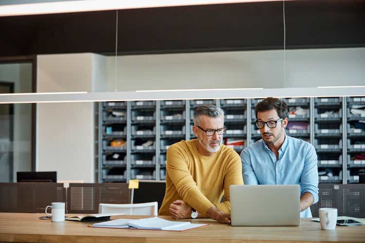 Businessmen using laptop together at desk