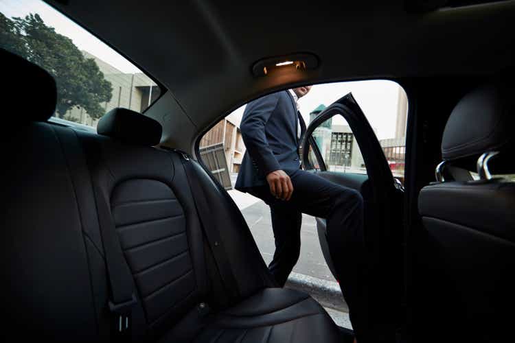 Businessman climbing into the back seat of the exclusive taxi