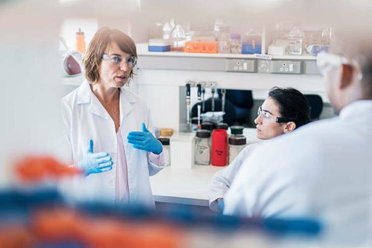 Chemist discussing with colleagues in laboratory