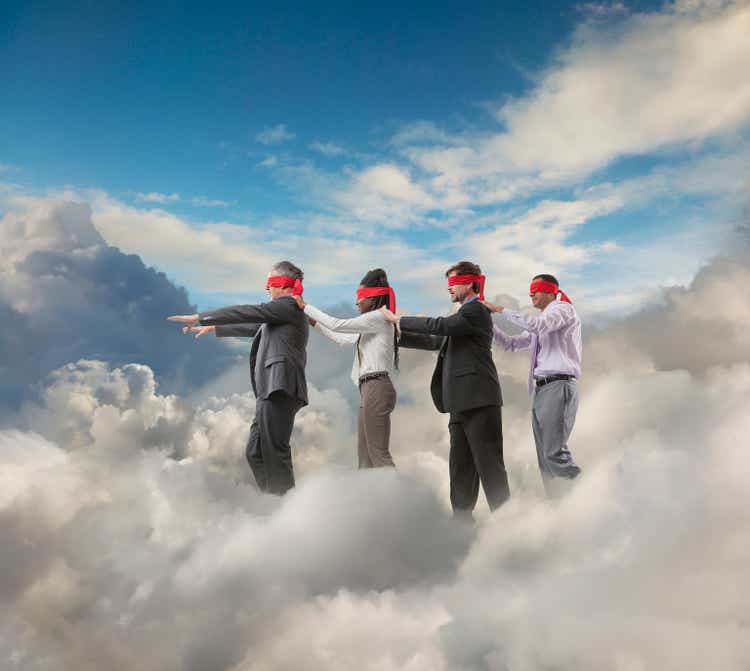 Blindfolded businesspeople walking in clouds