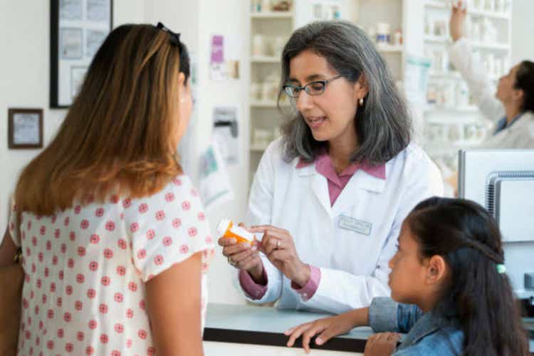 Pharmacist talking with customer about prescription bottle