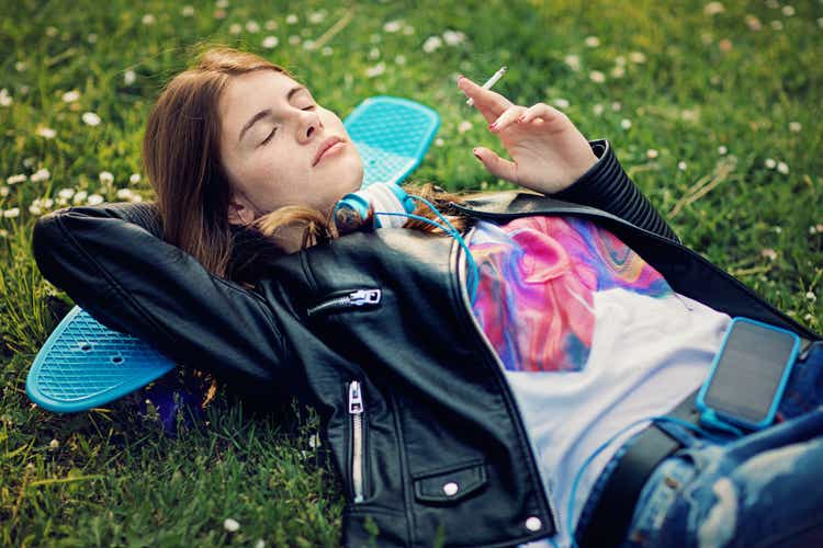 Teenage girl is lying down and smoking cigarette