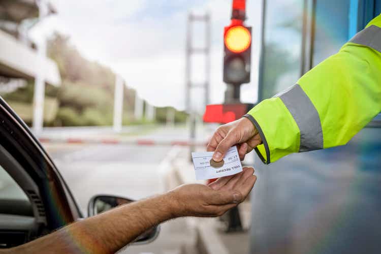 Driver in car paying toll booth at bridge, close up