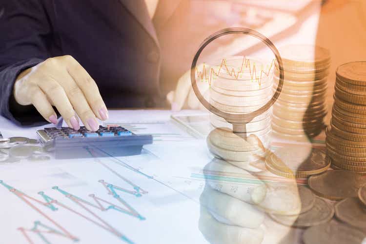 double exposure of business woman analyzing on financial graph report and stock chart, hand holding magnifying glass