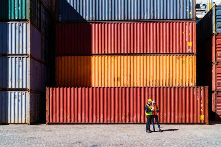 Workers having discussion against cargo containers