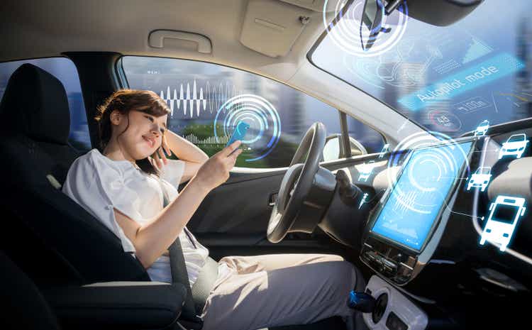 A woman using a smartphone in a self-driving car. Self-driving car. Autopilot. automotive technology.