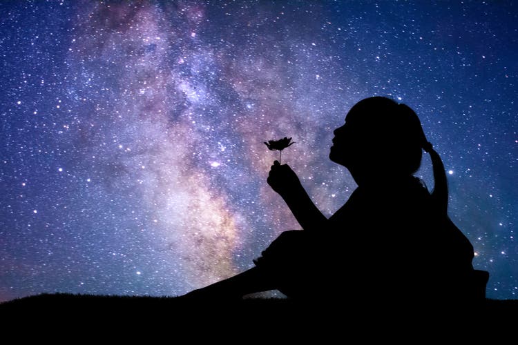 Silhouette of little girl holding a flower