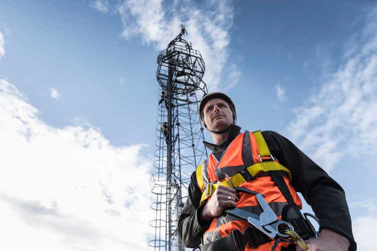 Transmission tower engineer with tower, low angle view