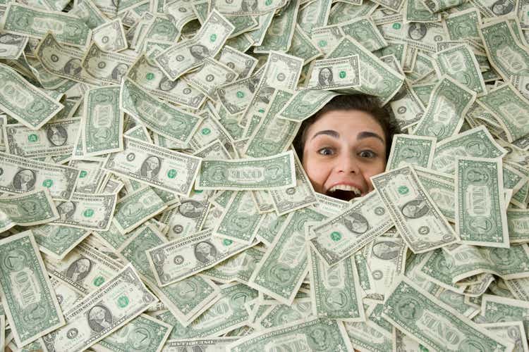 Woman"s face peeking out of a pile of money