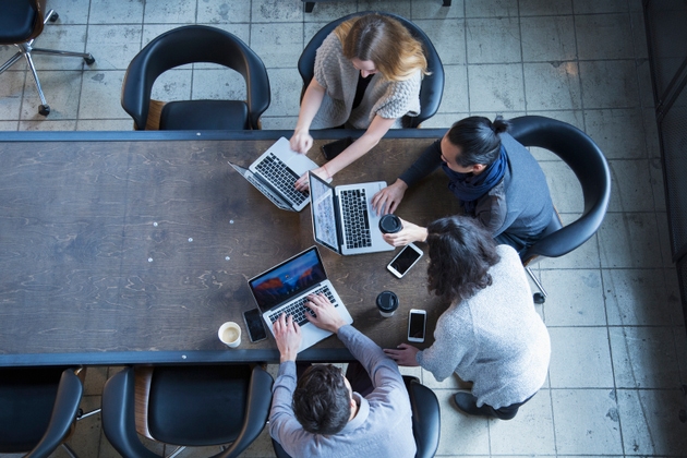 Business people in office meeting using laptops
