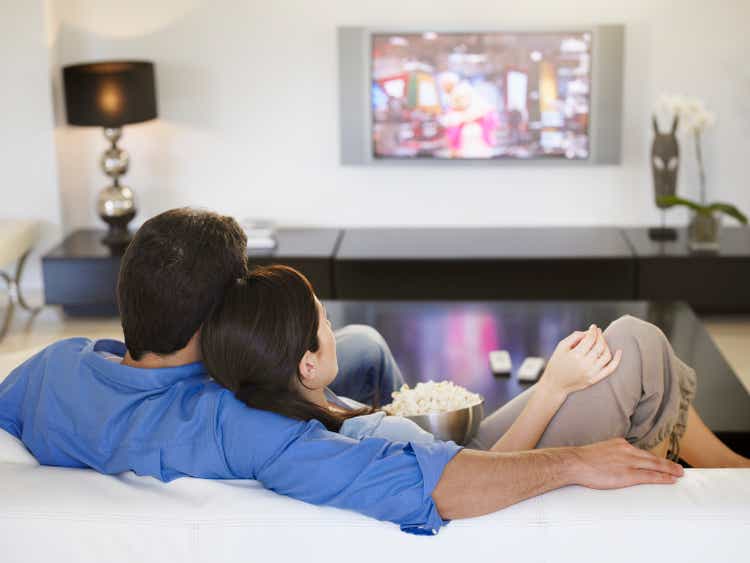 Couple watching television together and eating popcorn