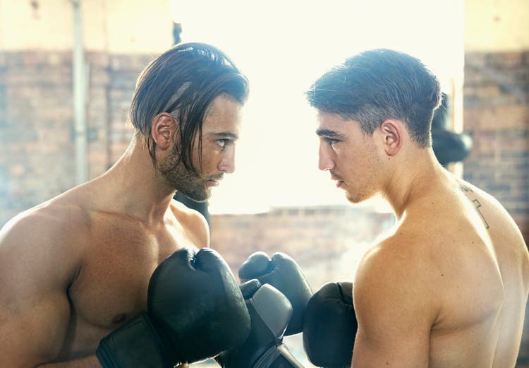Confident Hispanic boxers face to face in gymnasium