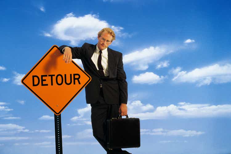 Businessman leaning on detour sign