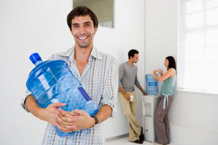 Man carrying water bottle and people at water cooler