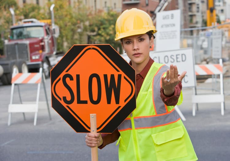 Hispanic female construction worker holding slow sign