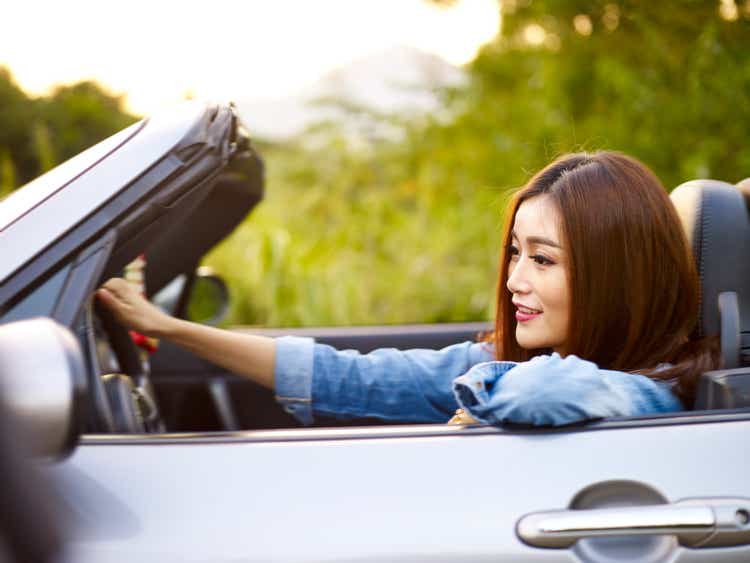 young asian woman driving a sports car