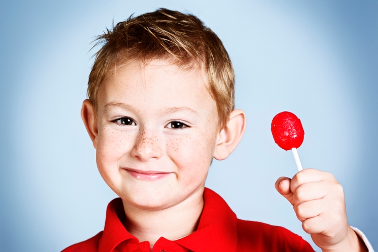 Smiling pre-school boy holds up red red lollipop