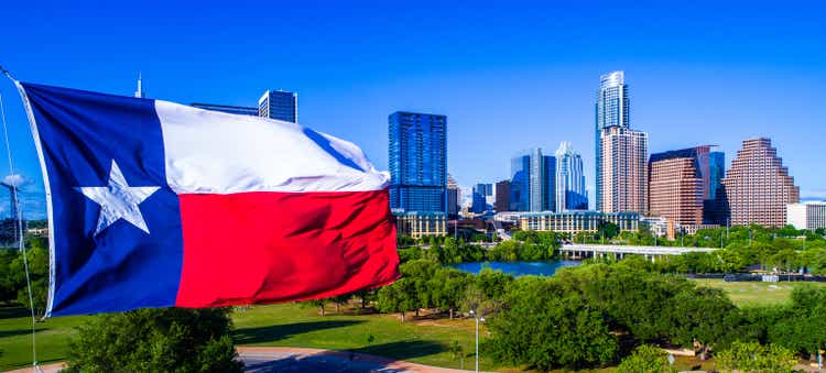 Perfect Texas Flag waving in the wind in front of Austin Texas Skyline Cityscape wide