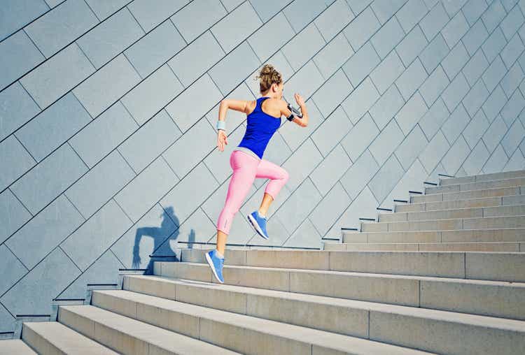 Girl is runing on the city stairs and listening the music