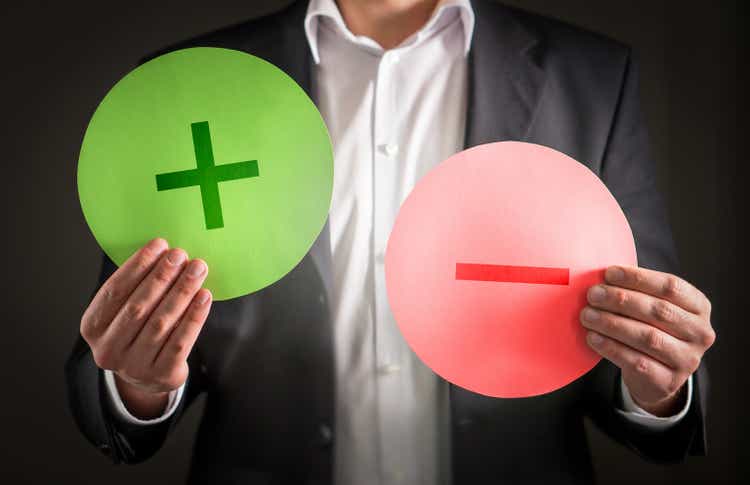Pros and cons concept. Business man with cardboard plus and minus symbol signs.