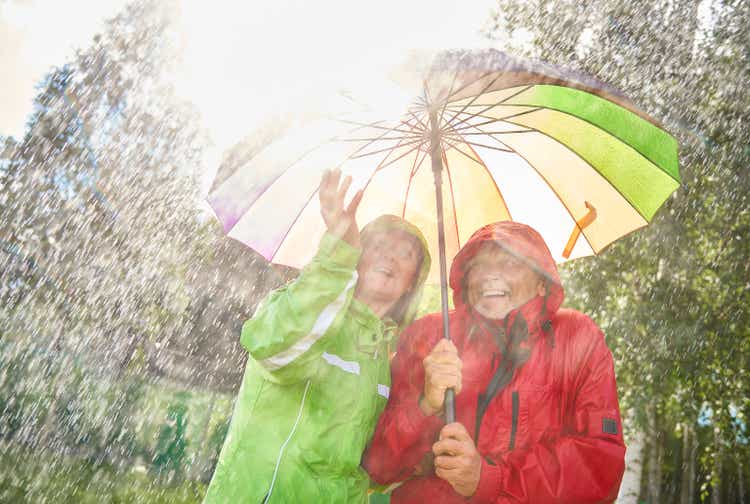 Happy couple standing with umbrella