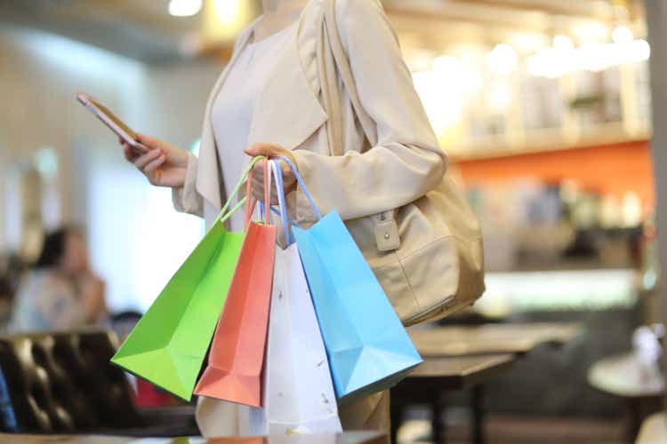 Cropped image of woman with shopping bags using a mobile phone