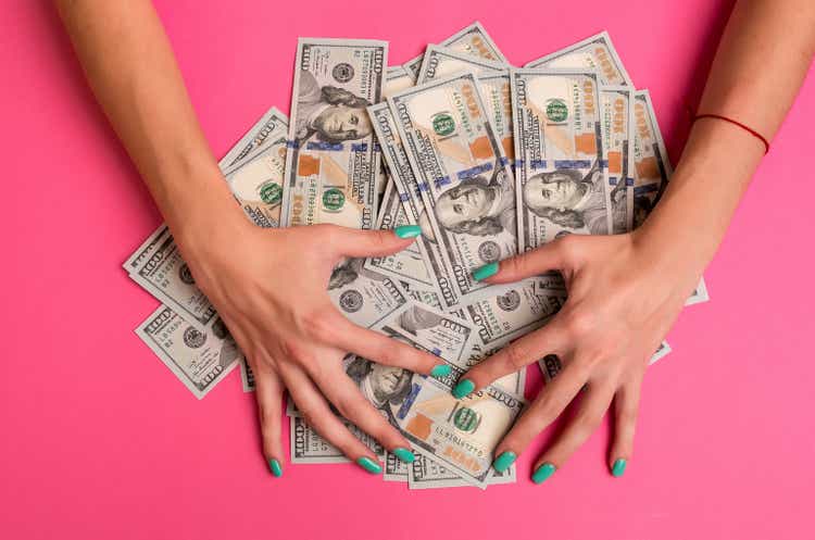 A woman is holding money in her hands. Pink background. Top view copy space