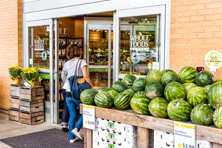 People, women, female entering Whole Foods Market grocery store building in city in Virginia with autumn displays and watermelons