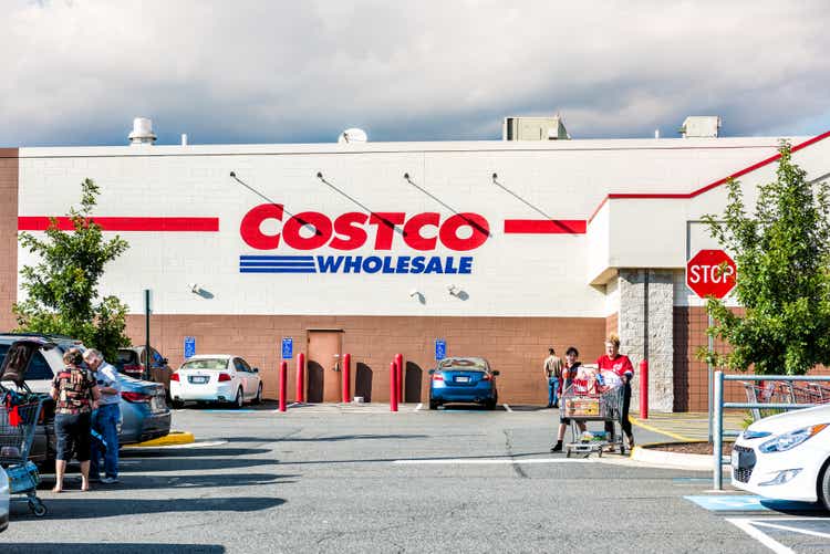 People with shopping carts filled with groceries goods, products walking out of Costco store in Virginia in parking car lot