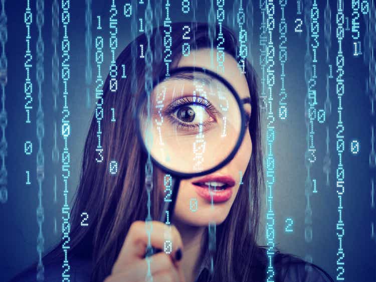 Investigation surveillance of cyber crime concept. Curious woman looking through a magnifying glass and computer binary code background