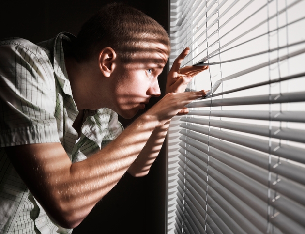 Man looking through the blinds.