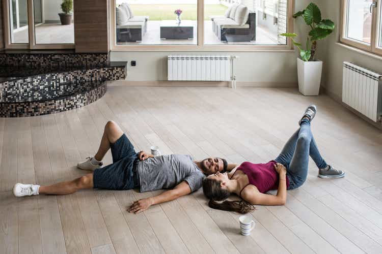 Young happy couple relaxing on a parquet floor at their new apartment.