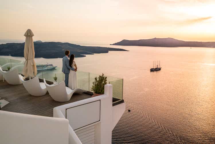 Authentic Wealth - rich couple standing on terrace with amazing sea view