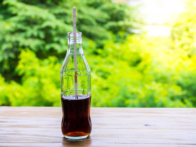 Glass bottle filled with cola and a straw