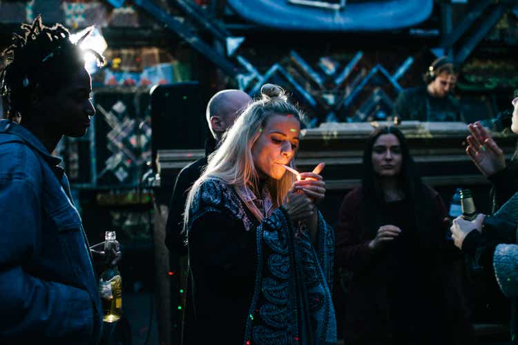 Young Partygoer Lighting A Joint While Dancing With Friends