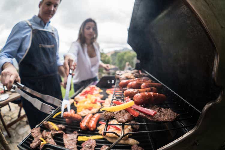 Happy couple checking the food on a BBQ