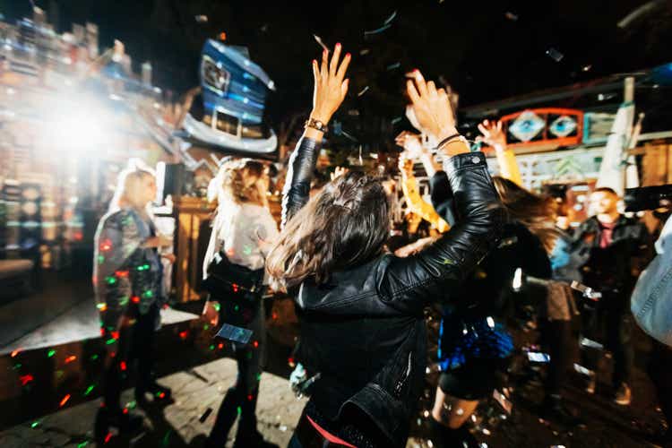 Young Woman Throwing Hands In Air While Dancing At Open Air Nightclub