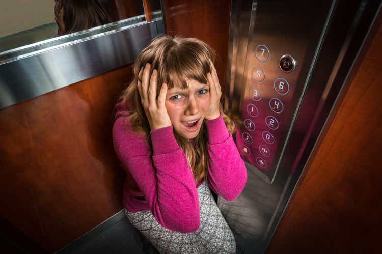 Shocked woman with claustrophobia in the moving elevator
