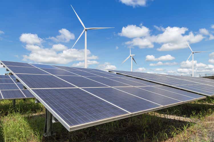Rows array of polycrystalline silicon solar panels and wind turbines generating electricity in hybrid power plant systems station alternative renewable energy from natural