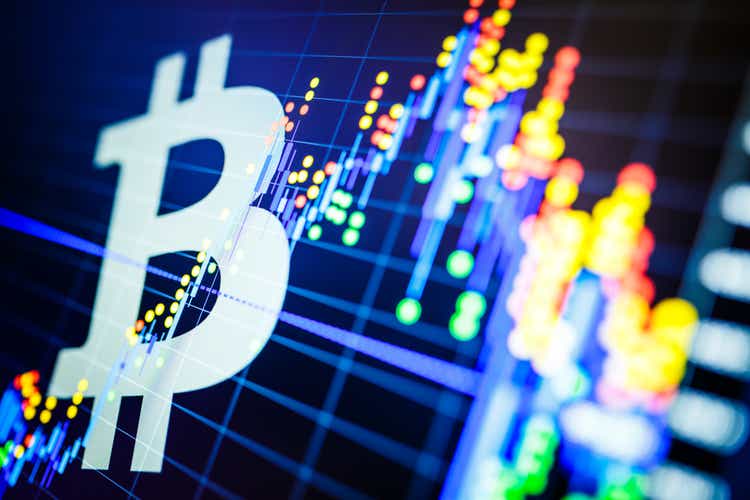 Data analysis in the stock market: the candles on the screen.  Analytics price change cryptocurrency BTC to USD (Bitcoin / US Dollar), the most popular pair in the world.  Large Bitcoin logo.