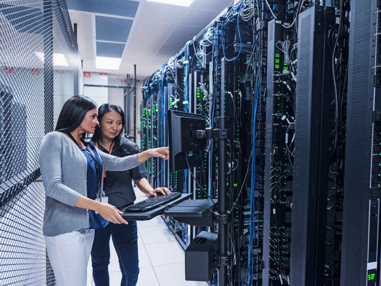 Two women working with computer in server room