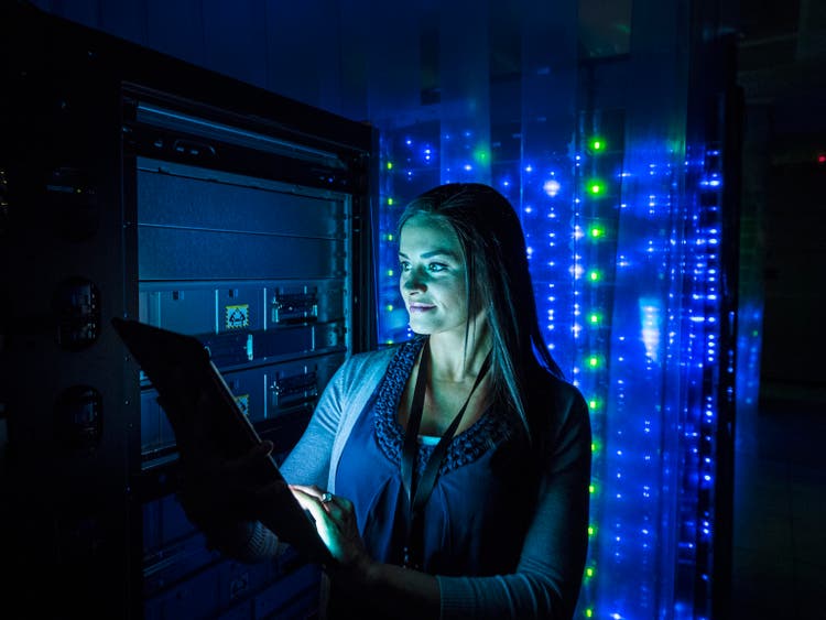 Woman working on digital tablet in dark server room
