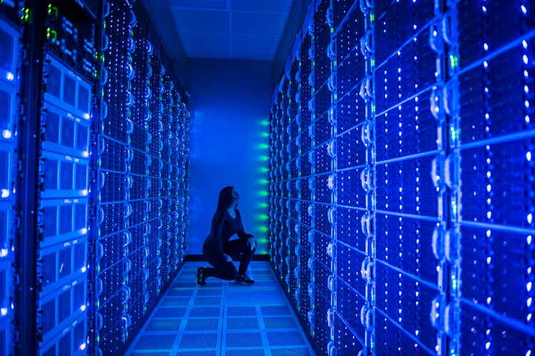 Side view of woman working in illuminated server room