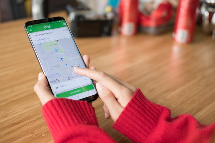 woman"s hand holding smartphone and using grab application for car sharing service