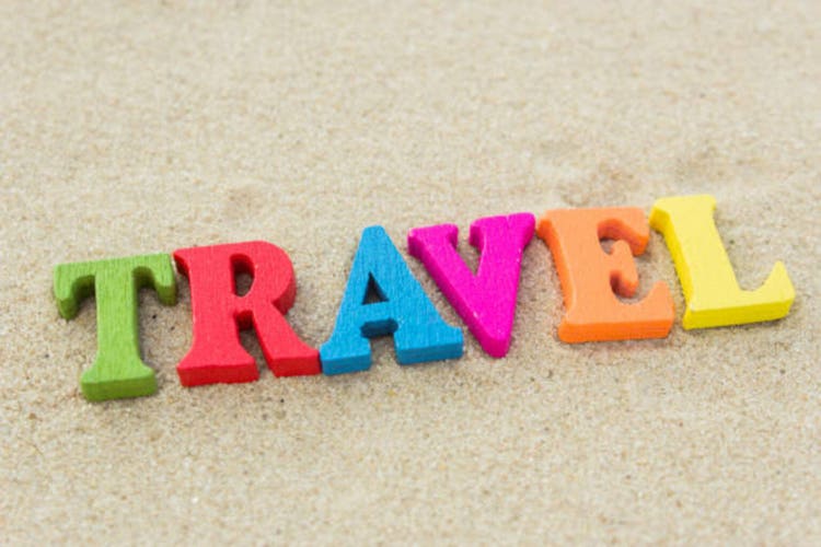 Word travel of colored wooden letters on sandy beach