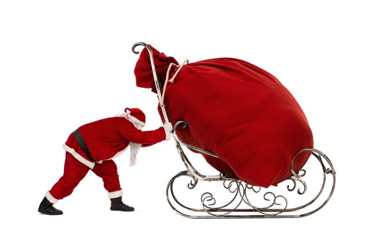 Santa Claus pushing sleigh with huge bag of christmas gifts on it