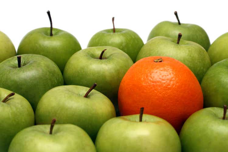 A pile of green apples and one orange