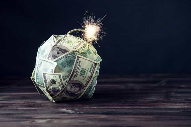 Bomb of money hundred dollar bills with a burning wick. Little time before the explosion. Concept of financial crisis