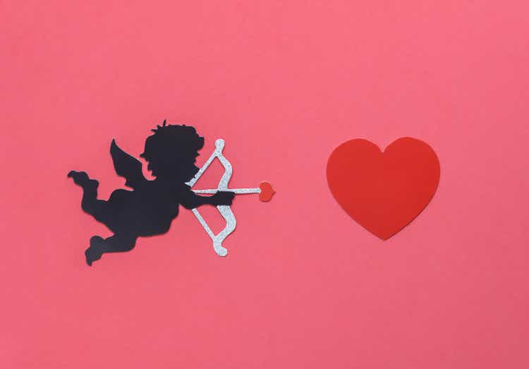 Flat lay aerial image of sign of valentines "s day background concept.DIY photo booth props the cupid shooting arrow to red heart on modern rustic pink wallpaper at home office desk studio.pastel tone