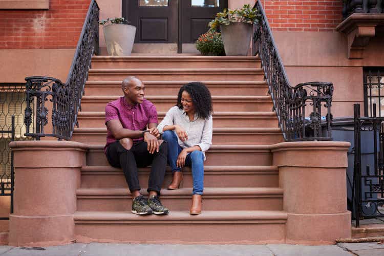 Paar zitten en praten over Stoop van Brownstone In New York City